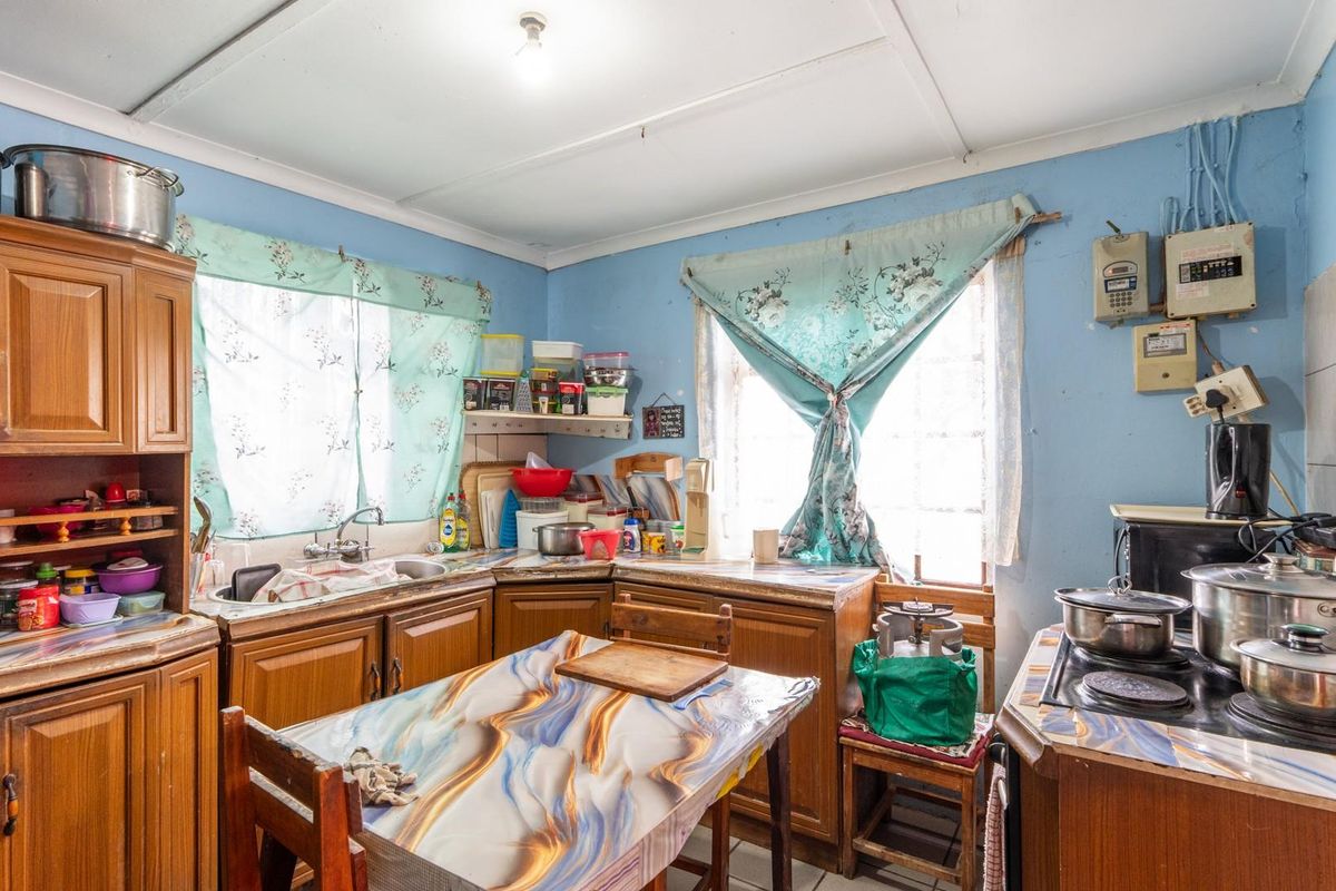 A dated kitchen featuring wooden cabinetry, laminate countertops, and a built-in hob, offering significant potential for modernization and renovation.