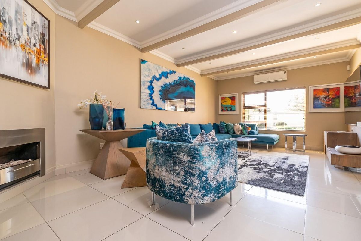 A well-maintained living room featuring polished tiled flooring, recessed ceiling lighting, a built-in fireplace, and a wall-mounted split-system air conditioner.