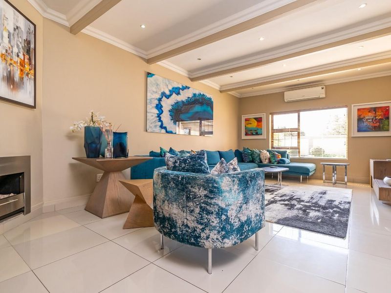 A well-maintained living room featuring polished tiled flooring, recessed ceiling lighting, a built-in fireplace, and a wall-mounted split-system air conditioner.