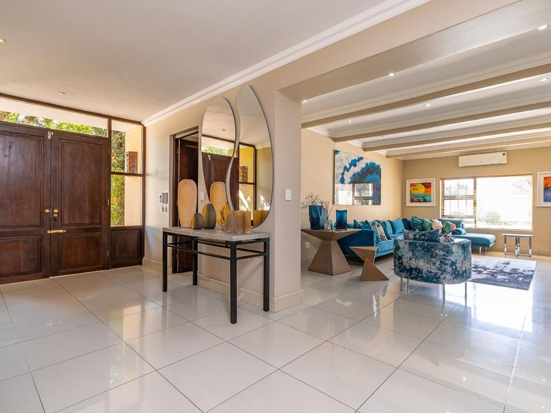 Spacious open-plan living area featuring polished porcelain tiles, exposed ceiling beams, recessed lighting, and a solid timber entrance door.