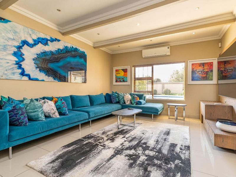 A well-maintained living room featuring recessed ceiling lighting, crown molding, tiled floors, and a wall-mounted air conditioning unit.