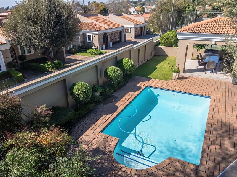 Aerial view of a townhouse complex backyard featuring a swimming pool, brick-paved patio area, and a covered outdoor entertainment space.