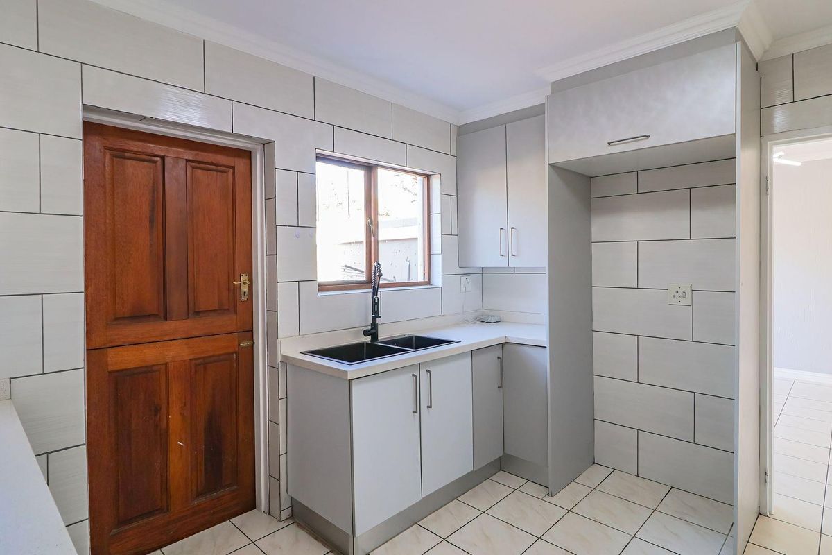 A clean, functional kitchen featuring modern grey cabinetry, a double basin sink with a contemporary tap, and tiled splashbacks throughout.