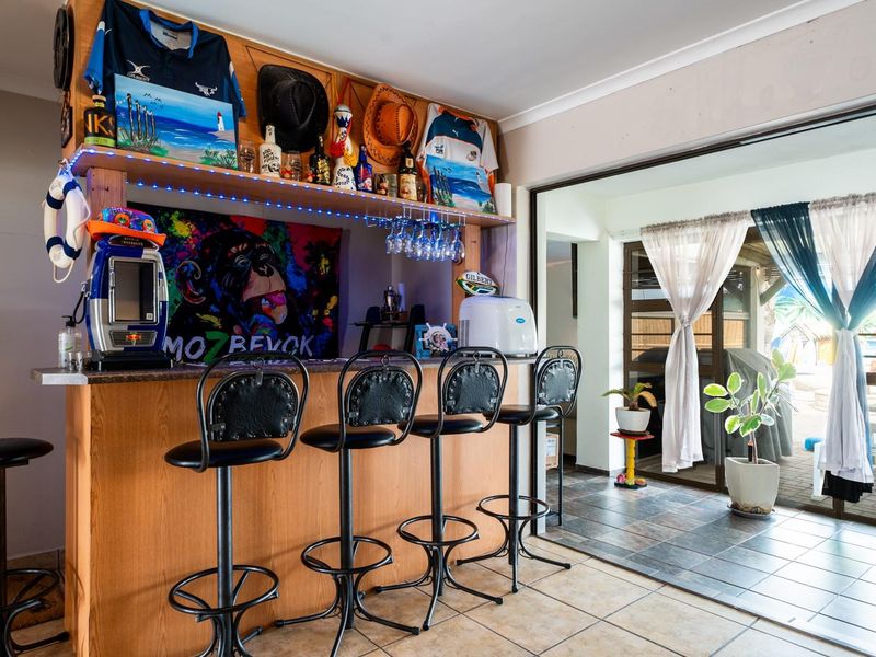 A dedicated indoor bar area featuring a built-in counter, glass storage, and direct access to an outdoor patio through sliding glass doors.