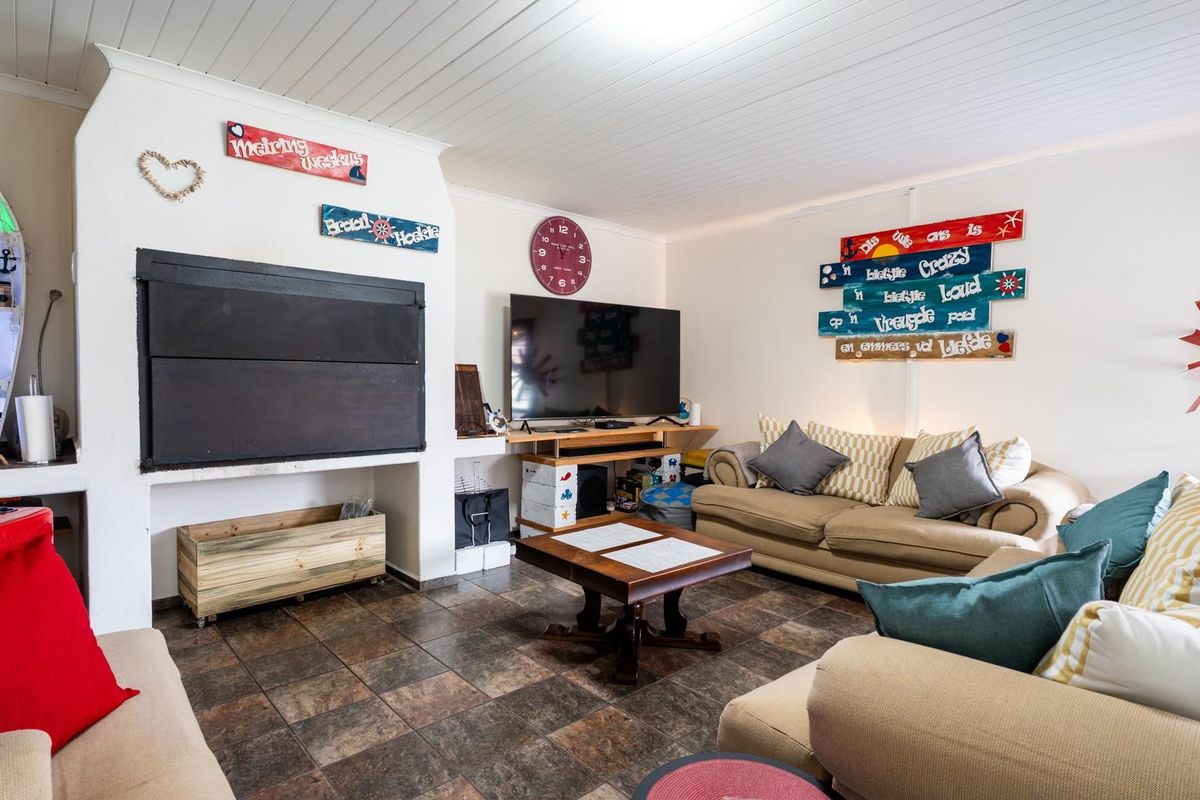 A living room featuring a built-in fireplace, tiled flooring, and a tongue and groove ceiling, offering a comfortable and functional living space.