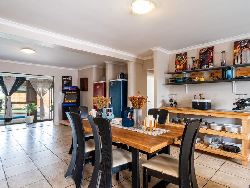 Spacious open-plan dining and living area featuring tiled flooring and large sliding glass doors leading to an outdoor patio space.