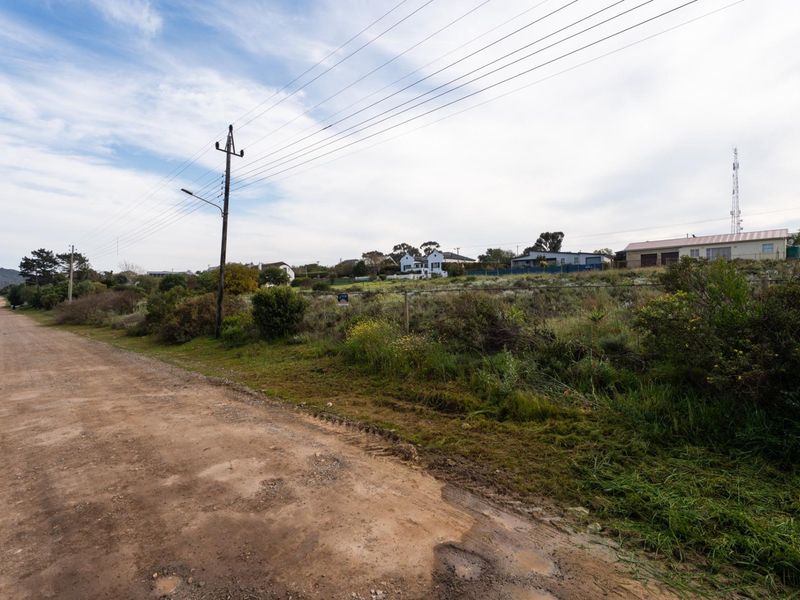 A view of the unpaved street frontage and surrounding residential landscape of the vacant land property.