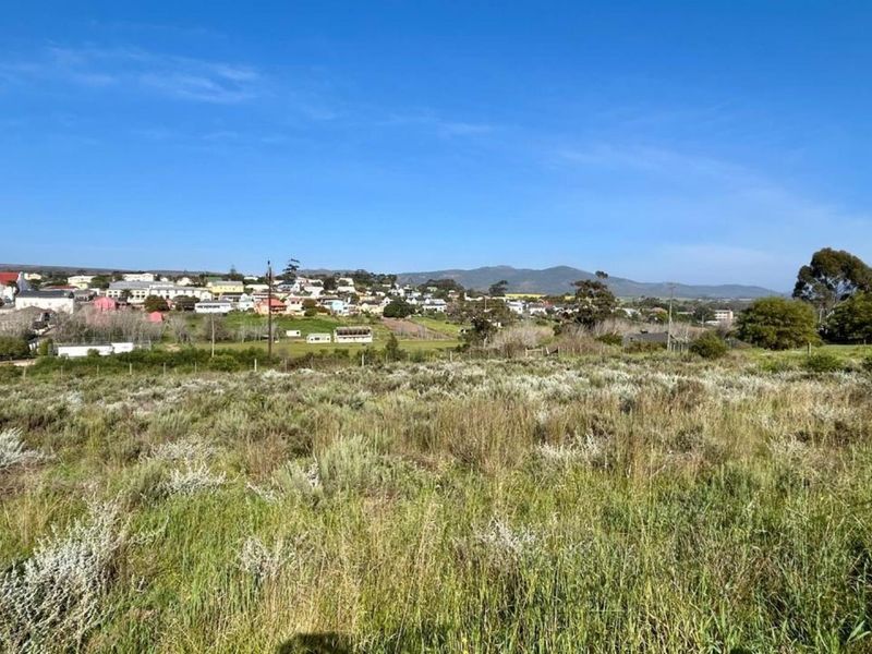 A wide-angle view of the vacant residential land, showcasing the surrounding landscape and distant town scenery.