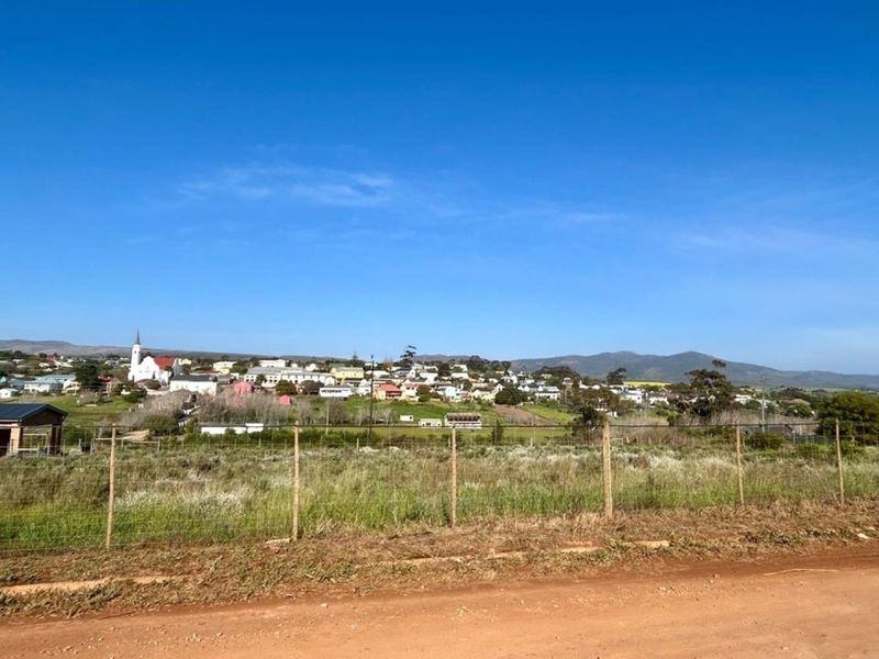 A scenic view of the surrounding town and landscape from the vacant residential plot, featuring a wire fence boundary.