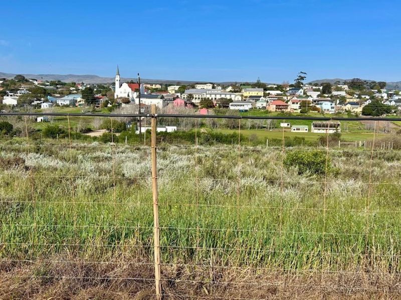 A view of the surrounding landscape and town from the vacant residential plot, featuring wire mesh boundary fencing.