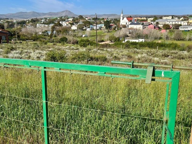 A view of the surrounding residential landscape and distant mountains, captured from the boundary of the vacant residential plot.
