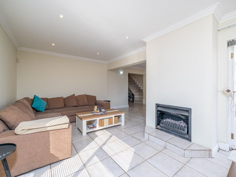 Spacious living room featuring tiled flooring, recessed lighting, and a built-in fireplace, with direct access to an outdoor patio area.