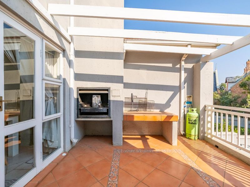 Covered balcony featuring a built-in braai, masonry prep counter, and tiled flooring, offering an ideal space for outdoor entertaining.