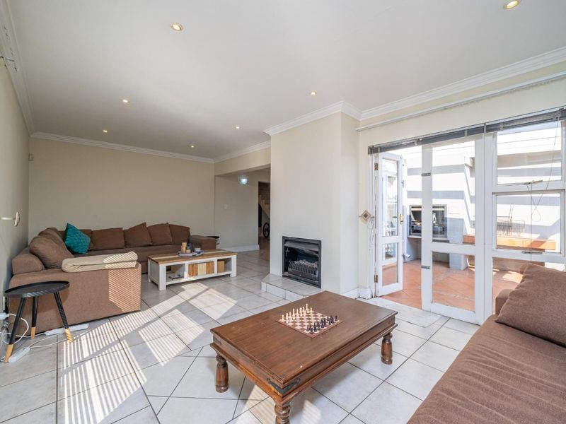 Spacious living room featuring tiled floors, a built-in fireplace, and direct access to an outdoor patio area through large glass sliding doors.