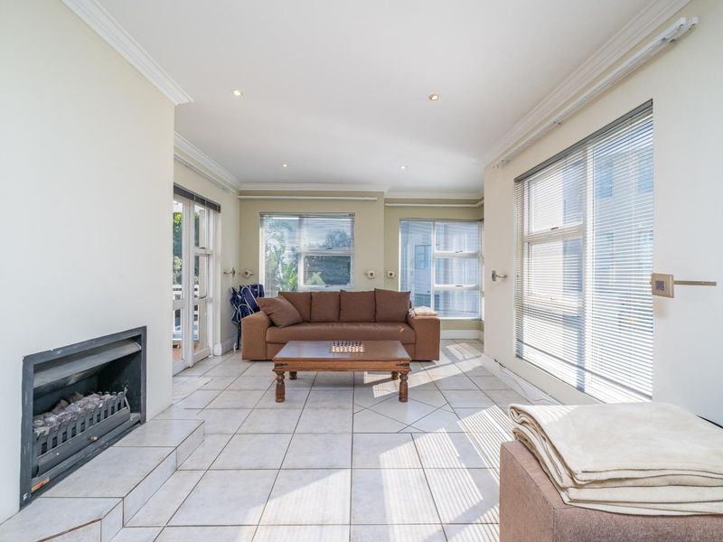 Spacious living room featuring tiled flooring, a built-in fireplace, and large windows with venetian blinds, offering a bright and functional layout.