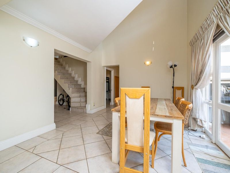 Dining area featuring vaulted ceilings, tiled flooring, and direct access to an outdoor patio through a glass sliding door.