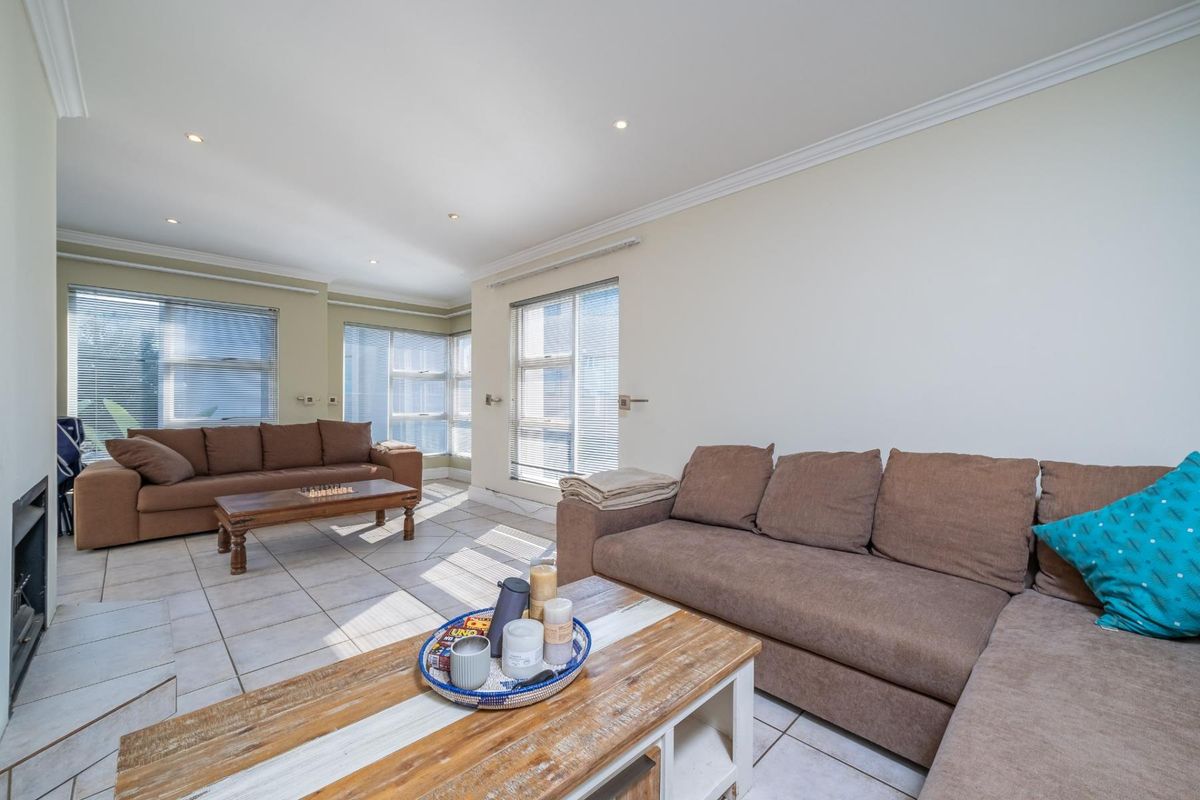 Spacious living room featuring tiled flooring, recessed downlights, and a built-in fireplace, with large windows providing ample natural light.