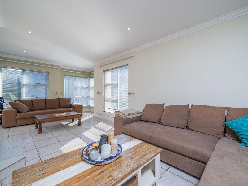Spacious living room featuring tiled flooring, recessed downlights, and a built-in fireplace, with large windows providing ample natural light.
