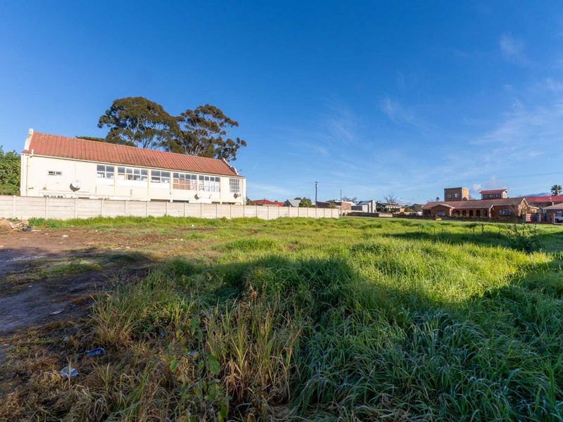 A vacant residential plot featuring a precast concrete boundary wall and open grassed area, suitable for future development.