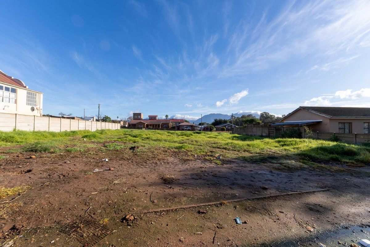A vacant residential plot of land featuring a precast concrete boundary wall and open, undeveloped ground with surrounding neighborhood views.
