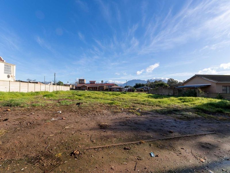 A vacant residential plot of land featuring a precast concrete boundary wall and open, undeveloped ground with surrounding neighborhood views.