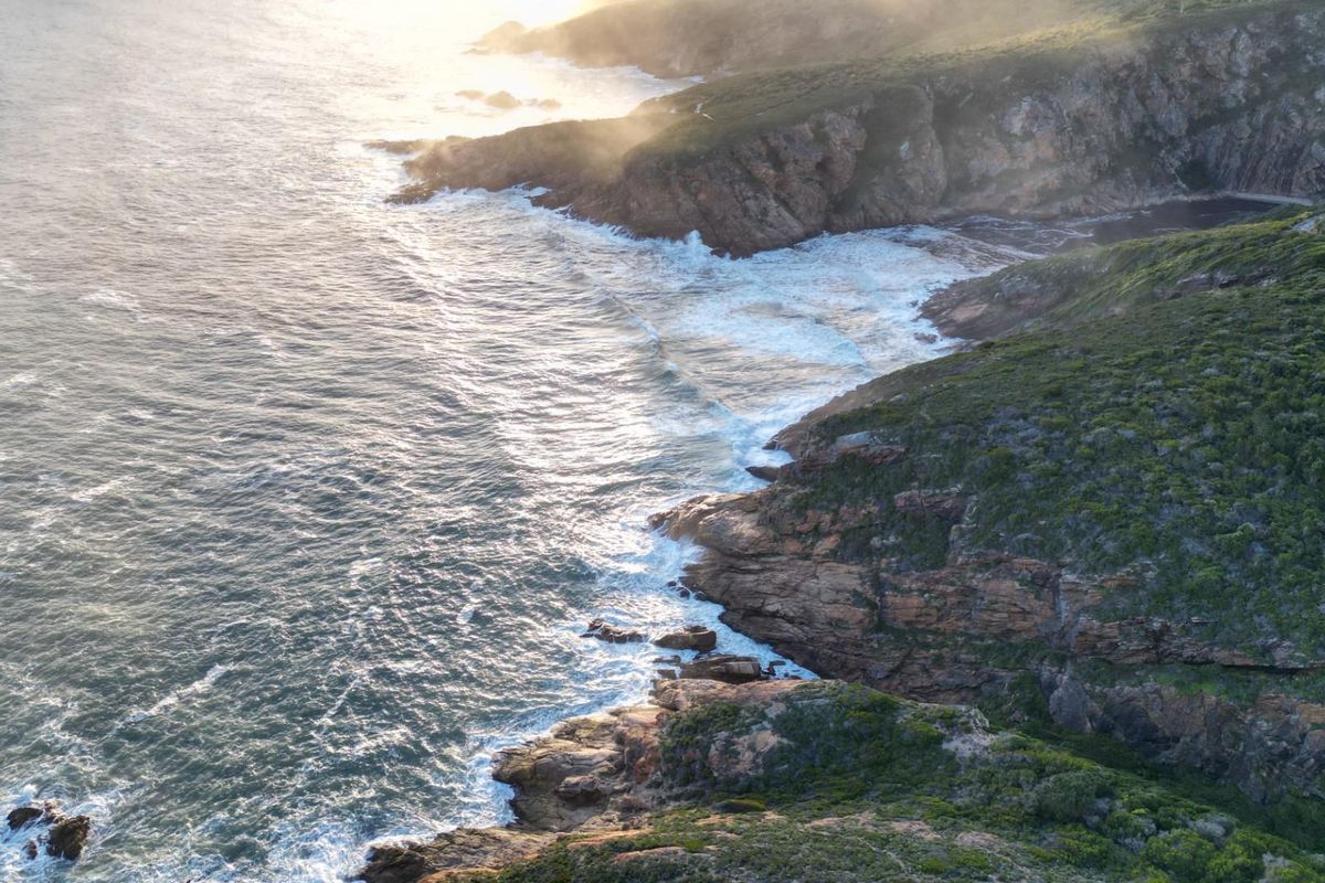 An aerial view of the rugged coastline, featuring dramatic cliffs meeting the ocean waves.