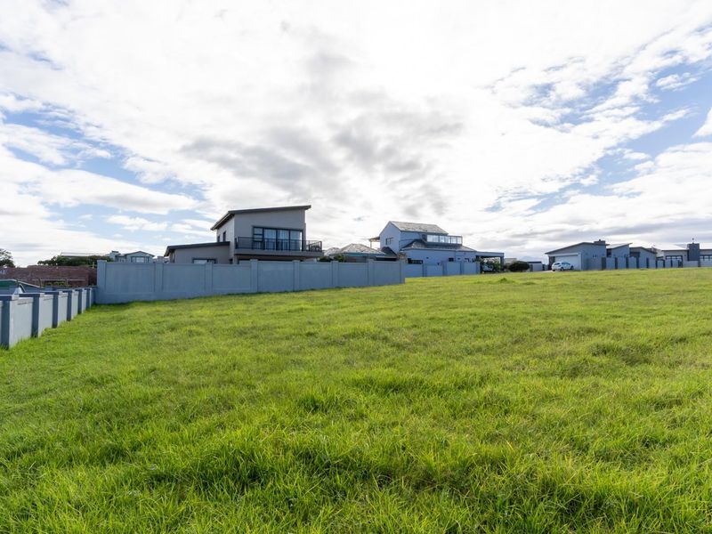 A spacious, level vacant residential plot featuring a well-maintained grass lawn and established perimeter boundary walls in a developed neighborhood.