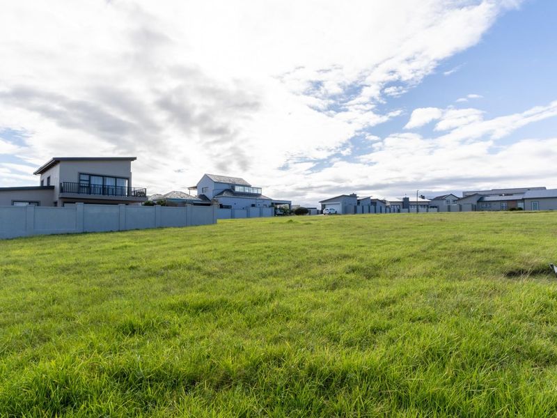 A vacant residential plot of land featuring established grass cover and boundary walling, situated within a developed residential neighbourhood.