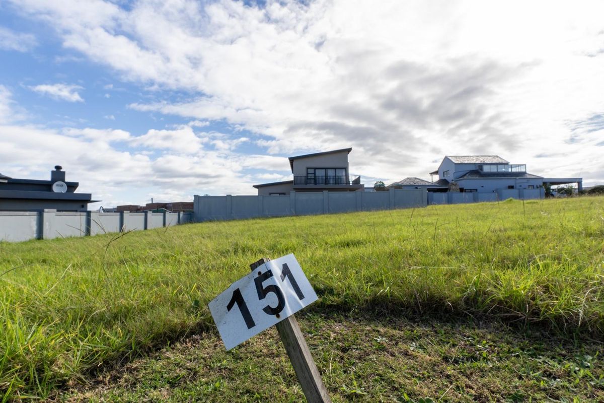 A vacant residential plot featuring a grassed surface and perimeter boundary wall, situated in a developed neighborhood.