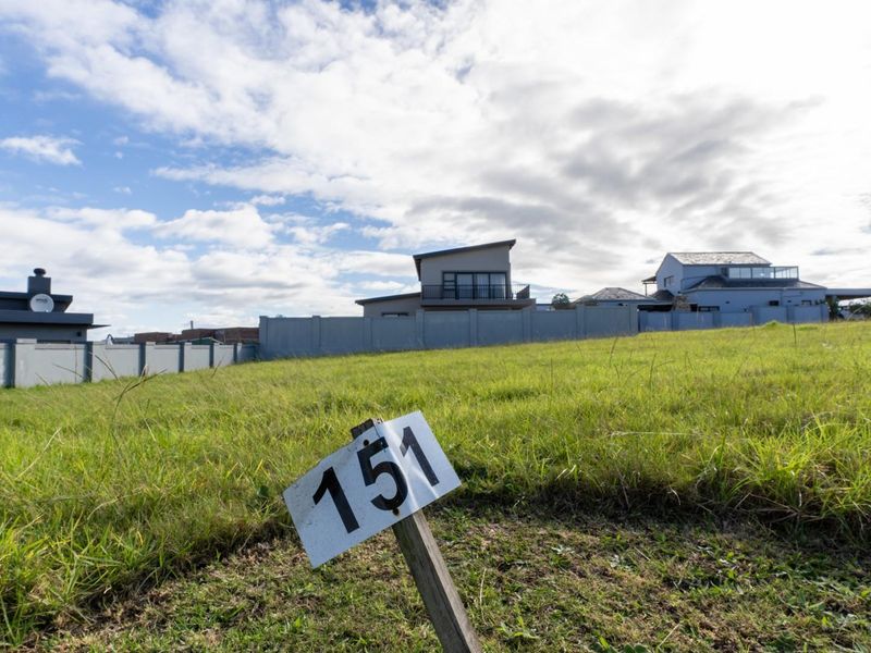 A vacant residential plot featuring a grassed surface and perimeter boundary wall, situated in a developed neighborhood.