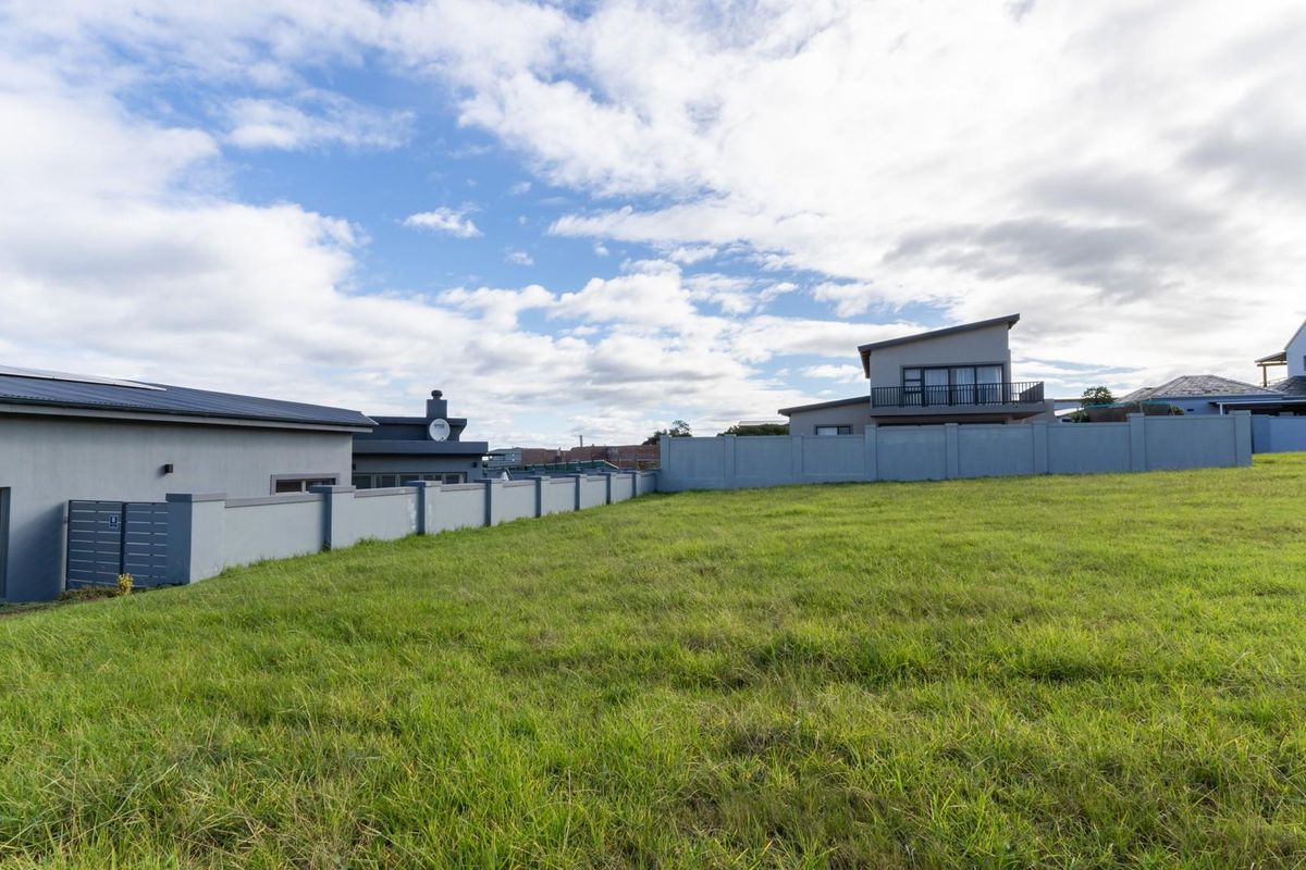 A vacant residential plot featuring a well-maintained grass lawn and perimeter boundary wall, situated in a developed neighborhood.