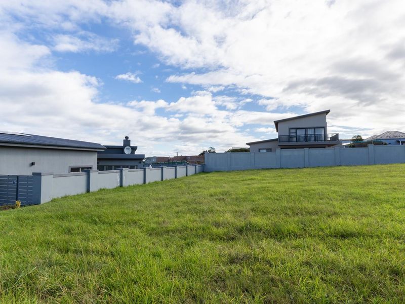 A vacant residential plot featuring a well-maintained grass lawn and perimeter boundary wall, situated in a developed neighborhood.
