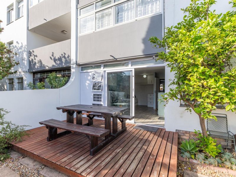 A private ground-floor patio featuring timber decking, providing seamless indoor-outdoor flow through a sliding glass door into the apartment living space.