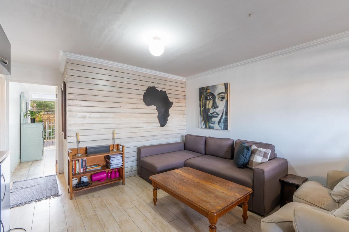 A living room featuring wood-look tile flooring and a decorative horizontal timber-clad feature wall, with direct access to an outdoor area.