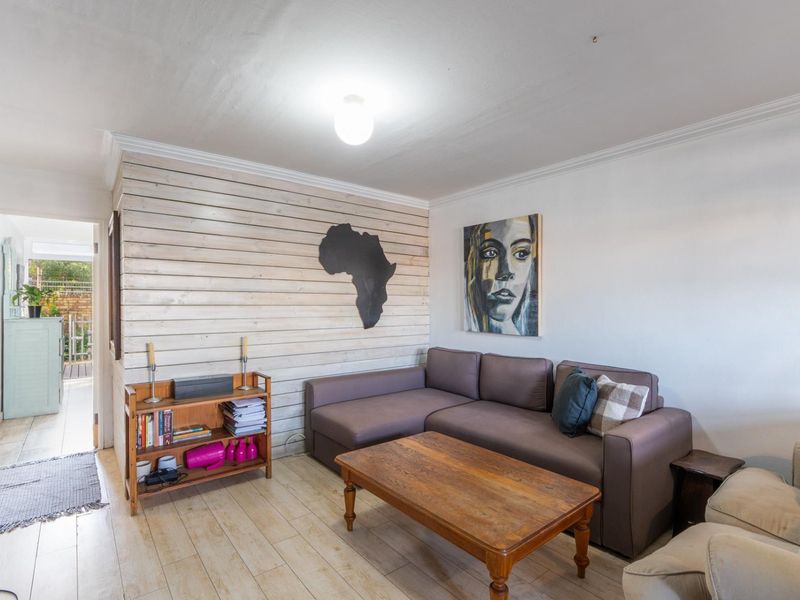 A living room featuring wood-look tile flooring and a decorative horizontal timber-clad feature wall, with direct access to an outdoor area.