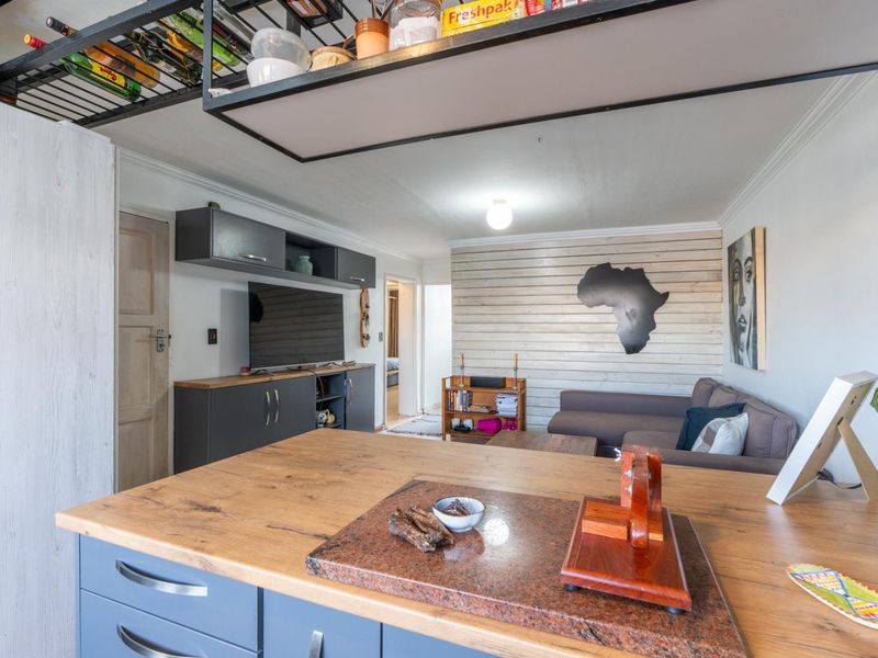 Open plan living area featuring a kitchen island with wooden countertop, overhead storage, and a feature timber-clad wall in the lounge section.