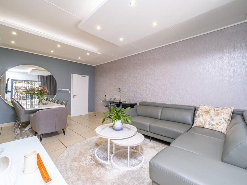 Spacious open-plan living and dining area featuring modern recessed ceiling lighting, neutral tiled flooring, and contemporary textured wall finishes.