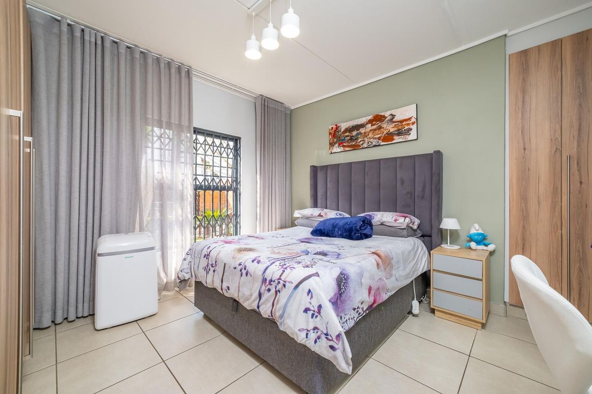 A well-maintained bedroom featuring tiled flooring, built-in cupboards, and a security gate, offering a clean and functional living space.