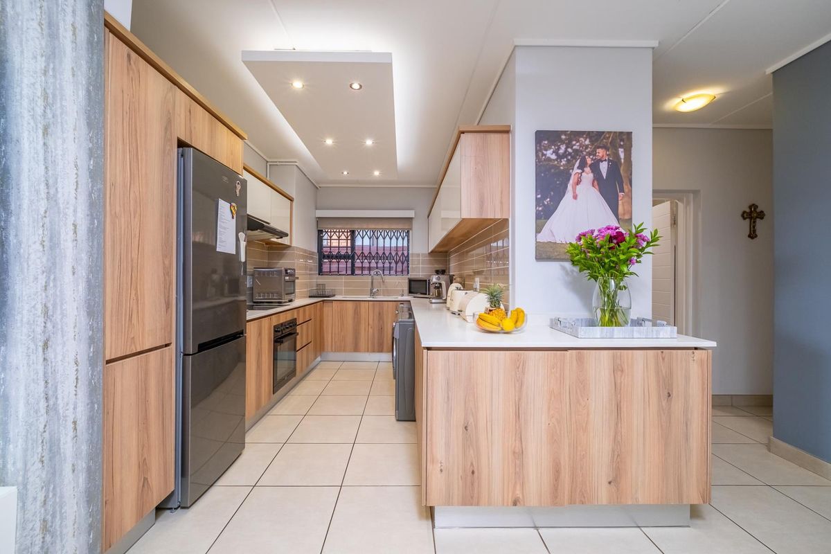 Modern kitchen featuring light wood-grain cabinetry, stone-look countertops, integrated appliances, and recessed ceiling lighting with a clean, functional layout.