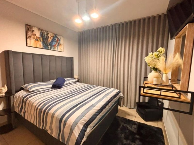 A well-maintained bedroom featuring tiled flooring, neutral wall finishes, and floor-to-ceiling curtains providing privacy and light control.