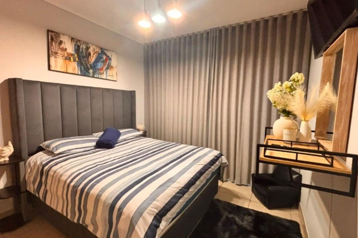 A well-maintained bedroom featuring tiled flooring, neutral wall finishes, and floor-to-ceiling curtains providing privacy and light control.