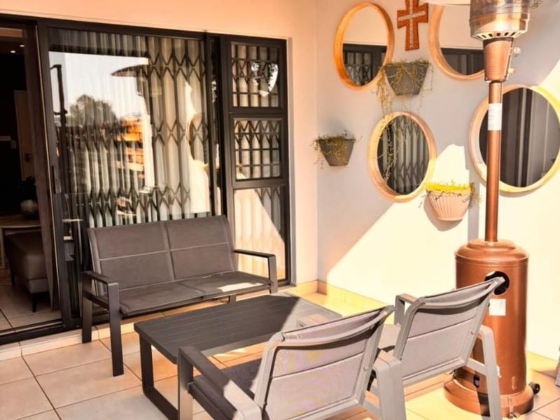 A covered patio area featuring tiled flooring, a pendant light, and sliding glass doors with integrated security gates.