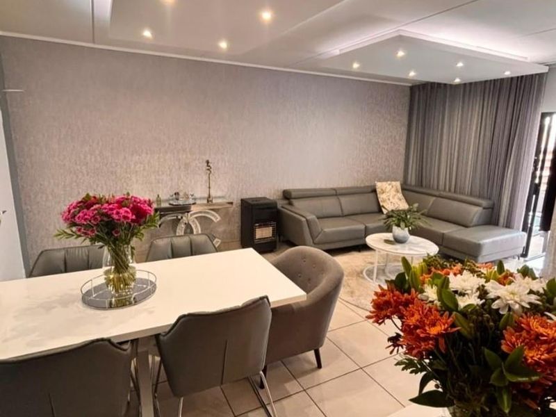 Spacious open-plan living and dining area featuring modern recessed ceiling panels with integrated downlights and neutral tiled flooring throughout.