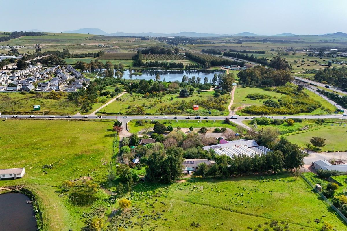 Aerial view of a commercial property featuring multiple structures, solar installations, and surrounding green space with access to main road infrastructure.