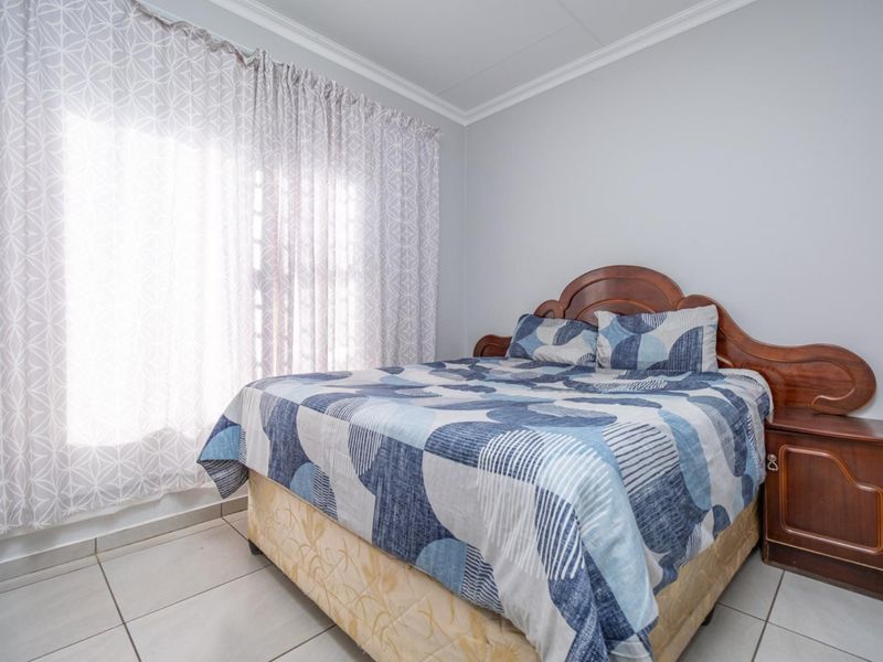 A functional bedroom featuring neutral wall tones, tiled flooring, and crown molding, providing a clean and simple living space.