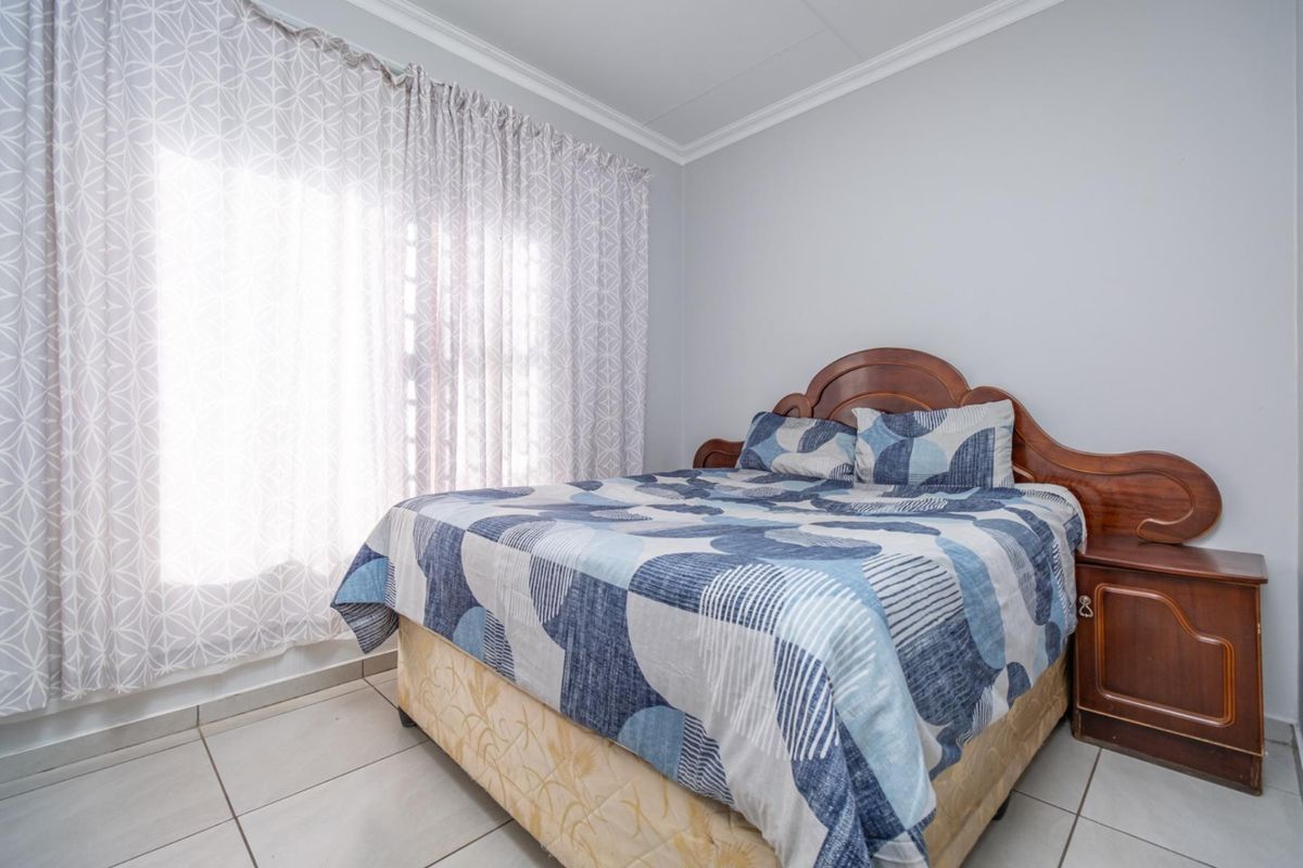A functional bedroom featuring neutral wall tones, tiled flooring, and crown molding, providing a clean and simple living space.