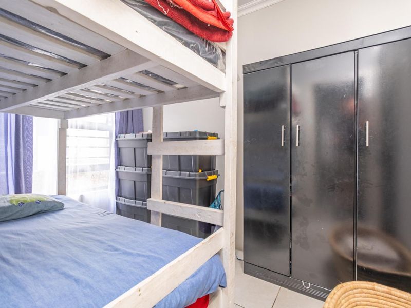 A bedroom featuring tiled flooring and a built-in wardrobe, providing functional storage space.