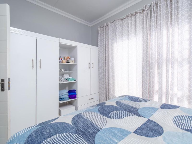 A well-maintained bedroom featuring built-in white cupboards with integrated shelving and elegant crown molding detail.