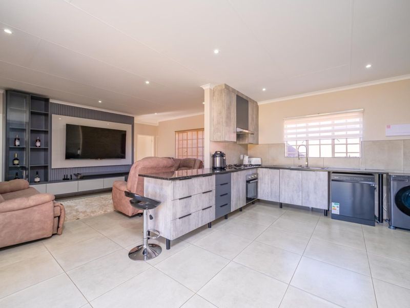 Modern open-plan living area featuring a contemporary kitchen with granite countertops, built-in appliances, and a seamless transition to the lounge with custom media cabinetry.