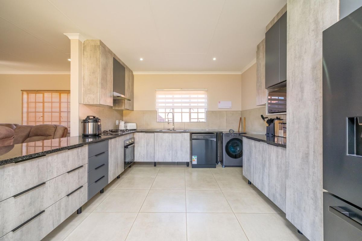 Modern kitchen featuring contemporary grey cabinetry, granite countertops, integrated appliances, and tiled flooring, offering a clean and functional workspace.